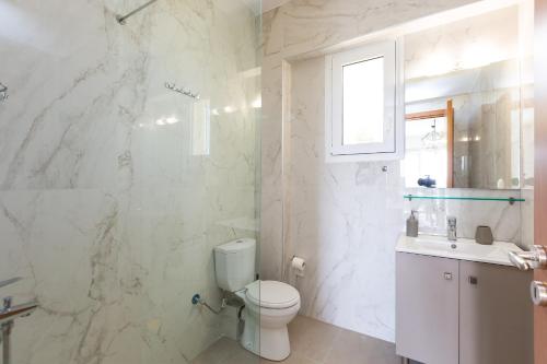 a white bathroom with a toilet and a sink at Vigla Suites in Rethymno Town