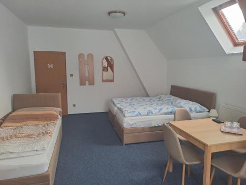a room with two beds and a table and a table and chairs at Pension Kachlicka in Skála