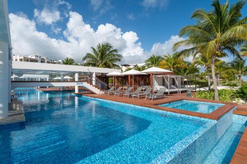 a swimming pool with chairs and a building at Marina Vista Retreat in Cancun La Amada in Cancún