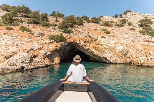 a person in a boat in a cave in the water at Virtu Suites in Agios Prokopios