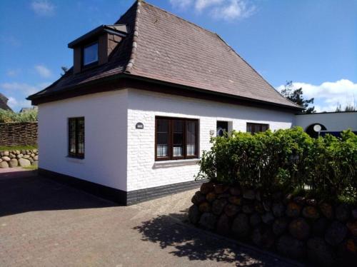 een klein wit huis met een zwart dak bij Kiekin in Wenningstedt