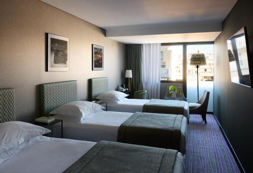 a hotel room with three beds and a window at President Hotel Athens in Athens