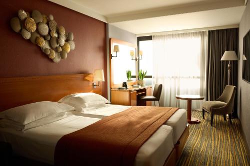 a hotel room with a large bed and a desk at President Hotel Athens in Athens