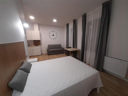 a bedroom with a large white bed and a chair at Apartamentos Recunchos in Ourense