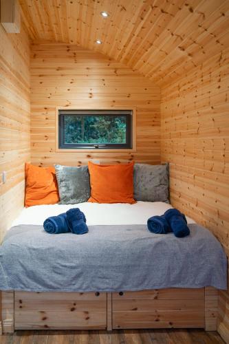 a bed in a wooden cabin with two pillows on it at Mount Ephraim Glamping Pods in Hernehill