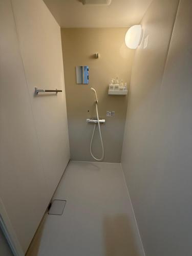 a bathroom with a shower with a hose at ゲストハウス 庵 Ann in Nachikatsuura