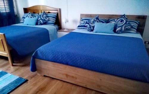 two beds in a bedroom with blue sheets and blue pillows at CasAdelinA in Arnaz