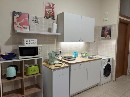 Una cocina con gabinetes blancos y lavadora. en Puccini Home "La Bohème", en Nola