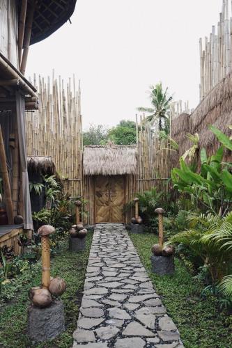 a garden with a stone path and a wooden door at Nivriti Bali in Sidemen
