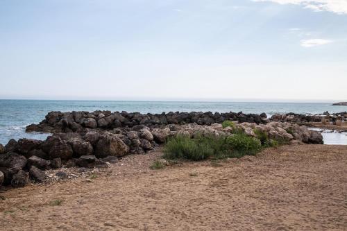 a group of rocks on a beach next to the ocean at Casa Ancora Fronte Mare in San Leone