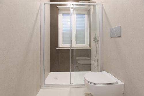 a white bathroom with a shower and a toilet at Casa Ancora Fronte Mare in San Leone