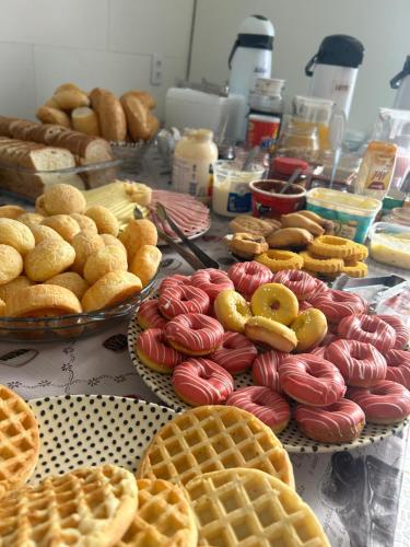 a table topped with lots of different types of donuts and waffles at Casa Pérolas do Mar in Balneário Camboriú