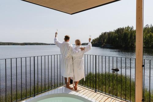 a couple standing on a balcony with their arms in the air at Sahanlahti Resort in Puumala