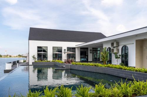 a house with a swimming pool next to a body of water at Pan Ville Resort in Pathum Thani