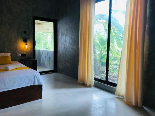 ein Schlafzimmer mit einem Bett und einem großen Fenster in der Unterkunft Midigama Home Stay Villa Apartment in Weligama