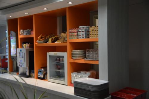 a store with orange shelves with dishes on them at HOTEL PREMIERE CLASSE Rouen Sud Oissel in Saint-Étienne-du-Rouvray