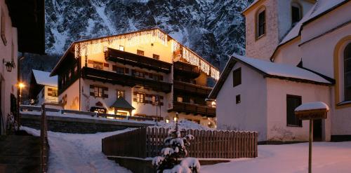 a building with a fence in the snow at night at Ferienhaus Alpen Lodge und die Gams in Neurur