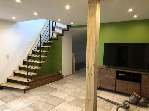 a living room with a staircase and a flat screen tv at La Ruine Single-family House with Hot Tub in Laveline