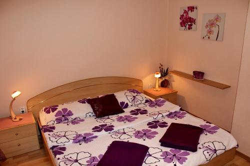 Un dormitorio con una cama con flores púrpuras. en Apartment Madlena en Brodarica