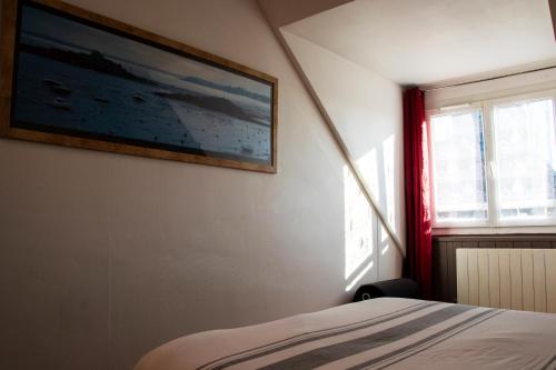 a bedroom with a bed and a painting on the wall at La Bigoudène in Saint-Cast-le-Guildo