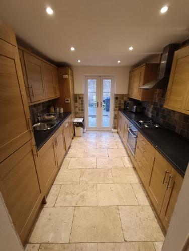 a large kitchen with wooden cabinets and a tile floor at 8 bed house 2 miles (7 Mins) from Newcastle centre in Newcastle upon Tyne