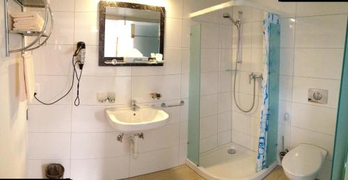 a bathroom with a sink and a shower and a mirror at Gästehaus Sonne in Bütschwil