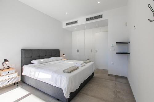 a bedroom with a large bed with white walls at Sage Villa by Vintage Travel in Tavronitis