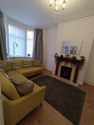 a living room with a yellow couch and a fireplace at 8 bed house 2 miles (7 Mins) from Newcastle centre in Newcastle upon Tyne