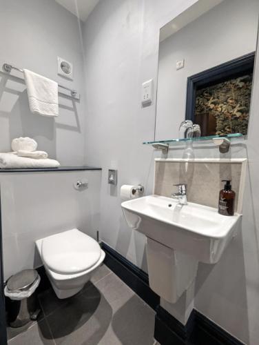a white bathroom with a toilet and a sink at The Coach House Suffolk in Lowestoft