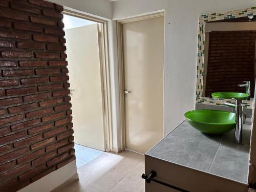a bathroom with a green sink and a brick wall at Casa los girasoles in La Rioja