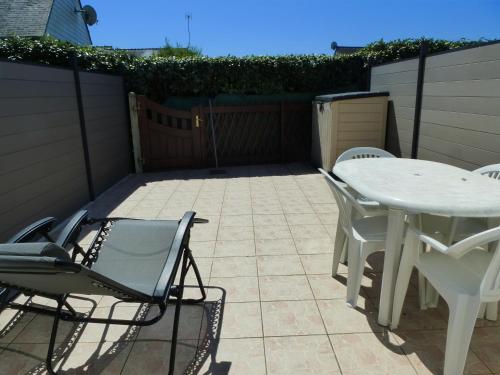 d'une terrasse avec une table et des chaises blanches. dans l'établissement Maison Sarzeau-St Jacques - 100 m de la mer, à Sarzeau