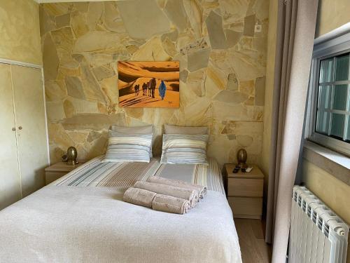 a bed in a room with a stone wall at A Casa Do Lago in Azeitao
