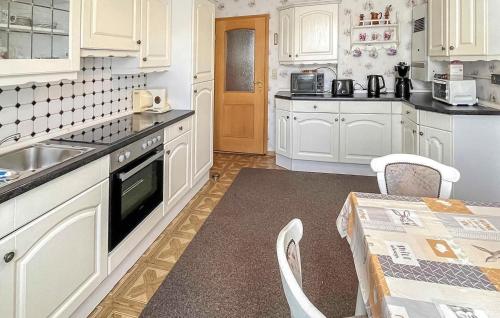 a kitchen with white cabinets and a table and a sink at Ferienwohnung Ueckermünde in Neuhof