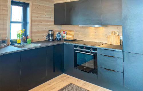 a kitchen with blue cabinets and a sink and a stove at Lovely Home In Vikeså With Kitchen in Vikeså