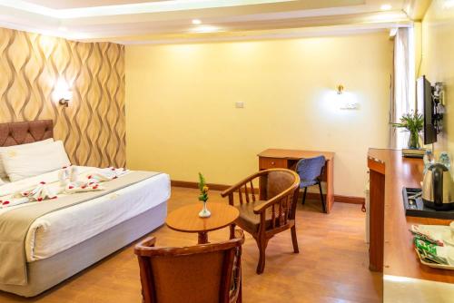 a bedroom with a bed and a table and a chair at Hillcourt Resort and Spa in Nakuru