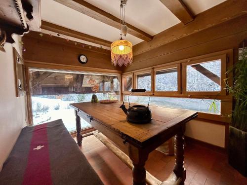 a dining room with a wooden table and windows at Rougemont Hideaway chalet by the river in Rougemont