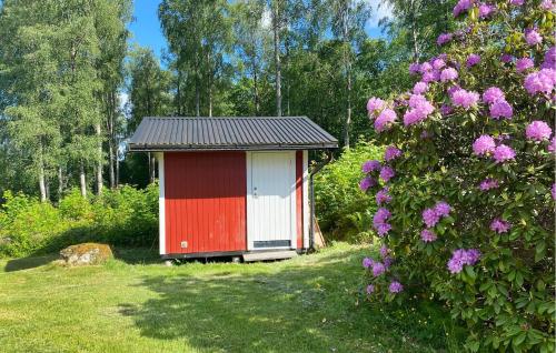 a red and white shed in a field with flowers at 3 Bedroom Cozy Home In Långserud in Rullan