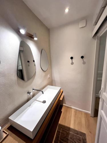 une salle de bain avec un lavabo blanc et un miroir dans l'établissement Maison authentique centre historique, à Villeneuve-lès-Avignon