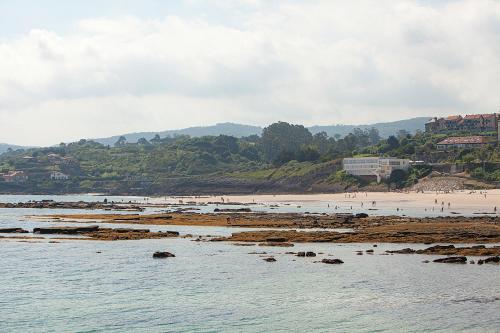 a beach with a group of people in the water at Hotel Josein in Comillas