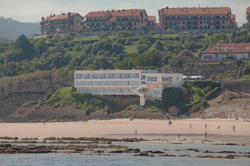 a building on top of a hill next to a beach at Hotel Josein in Comillas