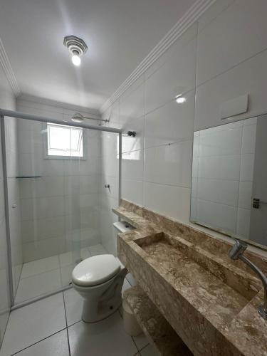 a bathroom with a toilet and a glass shower at Apartamento completo no Centro- Mongaguá Pé na areia in Mongaguá