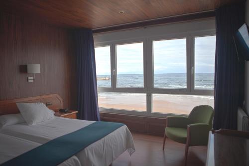a bedroom with a bed and a view of the ocean at Hotel Josein in Comillas