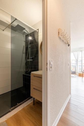 La salle de bains est pourvue d'une douche en verre et d'une commode en bois. dans l'établissement Hossegor - Piscine - Parking - Plage - Couple, à Hossegor