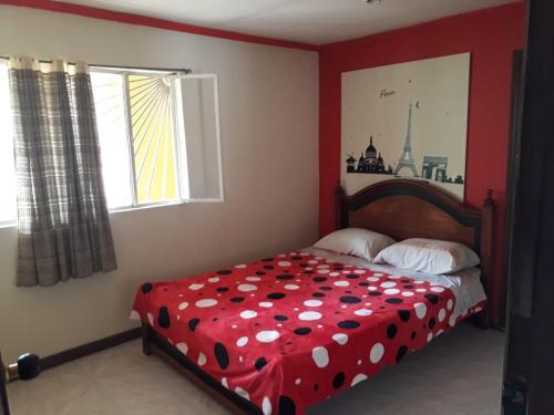 a bedroom with a bed with a red bedspread with polka dots at Finca Turistica VillaMaria in Tena