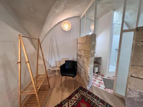 Cette chambre dispose d'une chaise et d'un mur en pierre. dans l'établissement Près d'Avignon, studio de charme avec vue, à Villeneuve-lès-Avignon