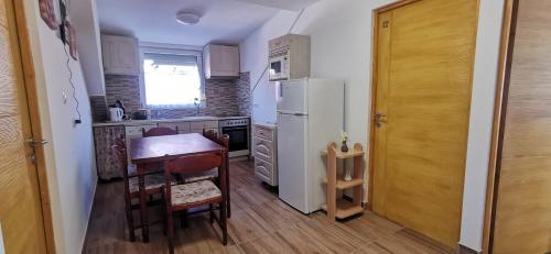a kitchen with a table and a white refrigerator at Rigófészek Apartmanház in Gárdony