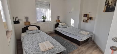 two beds in a small room with a window at Rigófészek Apartmanház in Gárdony