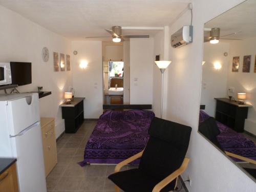 Ce petit appartement comprend un lit violet et une cuisine. dans l'établissement Studio Village Naturiste Purple, au Cap d'Agde