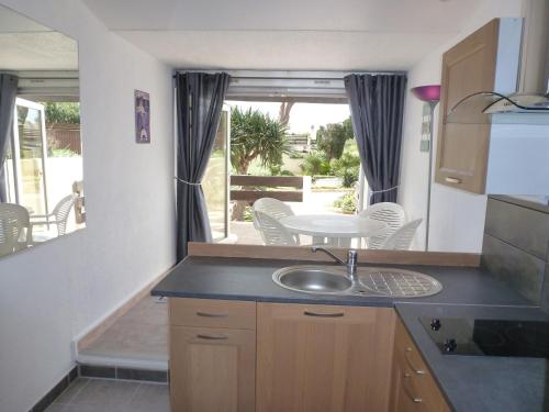 - une cuisine avec un évier, une table et des chaises dans l'établissement Studio Village Naturiste Purple, au Cap d'Agde