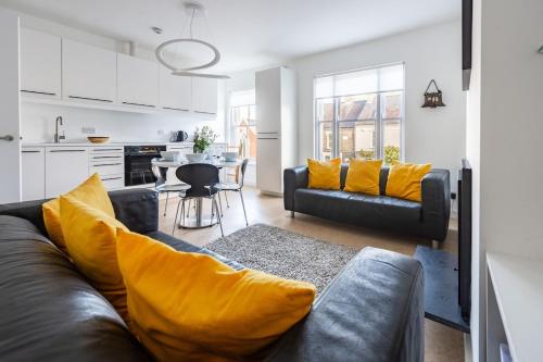 a living room with a black couch and yellow pillows at Swift Host - Sleeps 4 - Apartment - Great Location - Parking in Norwich